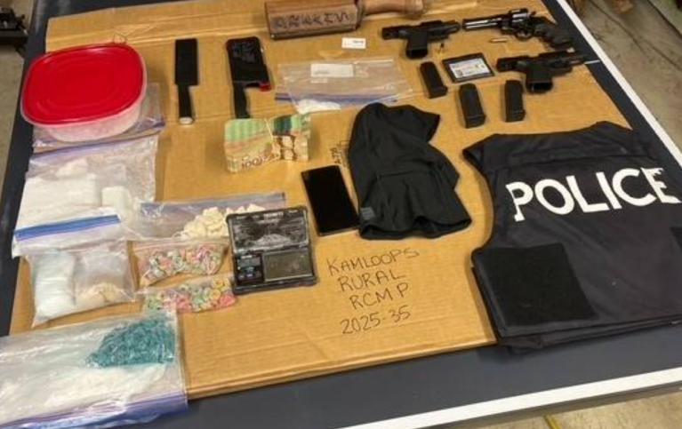 Kamloops RCMP find cash, drugs, guns in rented vehicle | iNFOnews.ca Drugs and guns laid out on a table with a police vest.