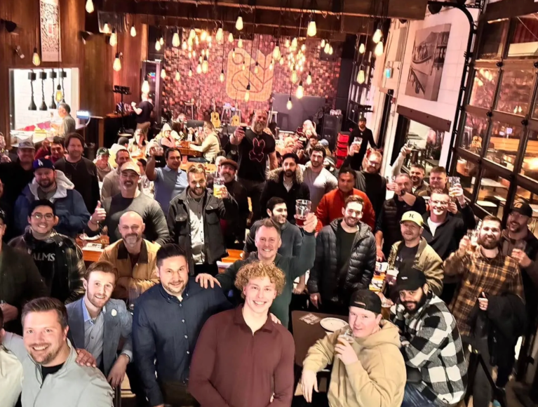 A big group photo of a bunch of guys at a bar.