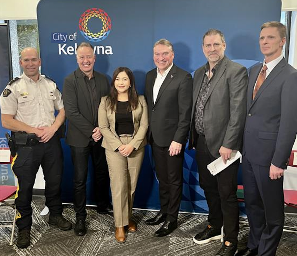 Six people standing in front of a City of Kelowna banner.