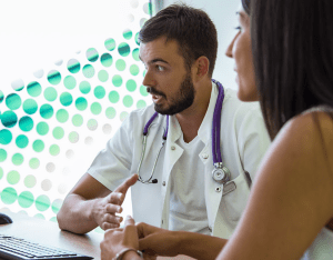 A doctor with a stethoscope speaking with a woman.