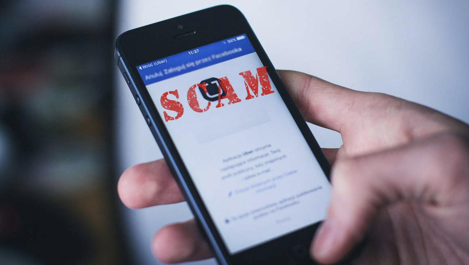 A cellphone with the word scam written in red text.