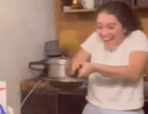A woman catching a pancake in a pan.