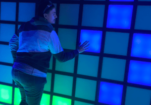 A woman pressing light-up, coloured tiles.
