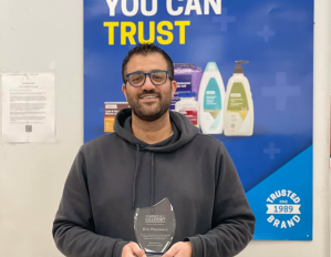 A man wearing a hoody holds an award.