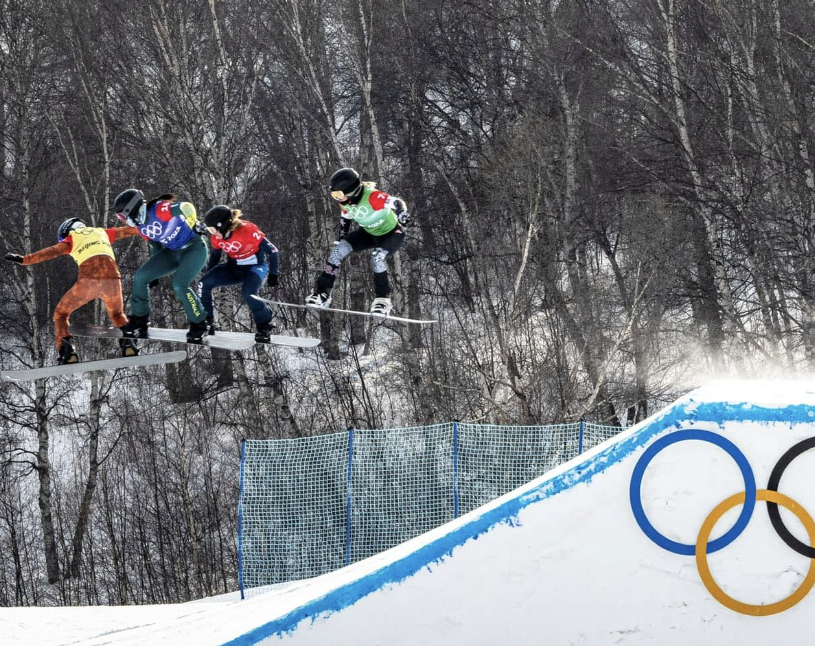 Snowboard cross riders going off a jump at the Beijing Olympics.