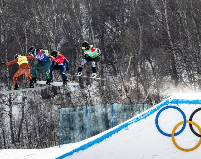 Snowboard cross riders going off a jump at the Beijing Olympics.