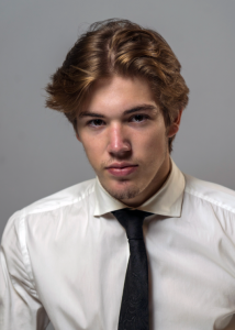 A young man in a shirt and tie poses for a photo.