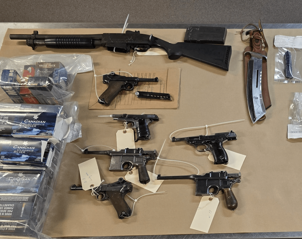 Guns and ammunition displayed on a table.