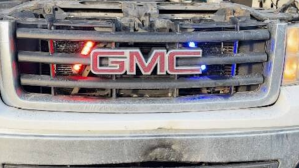 The grill of a pickup truck with red and white lights.