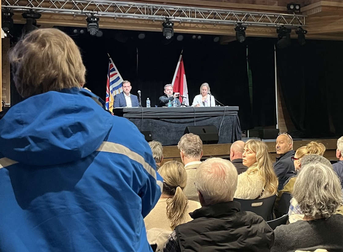 A crowd of people looking at three people on stage.