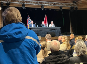 A crowd of people looking at three people on stage.