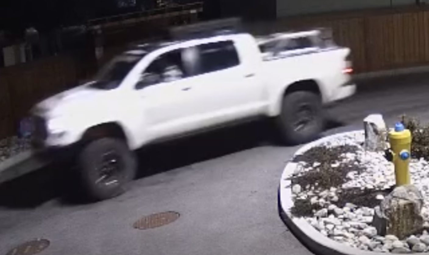 A blurry screen capture of a white, lifted pickup truck.