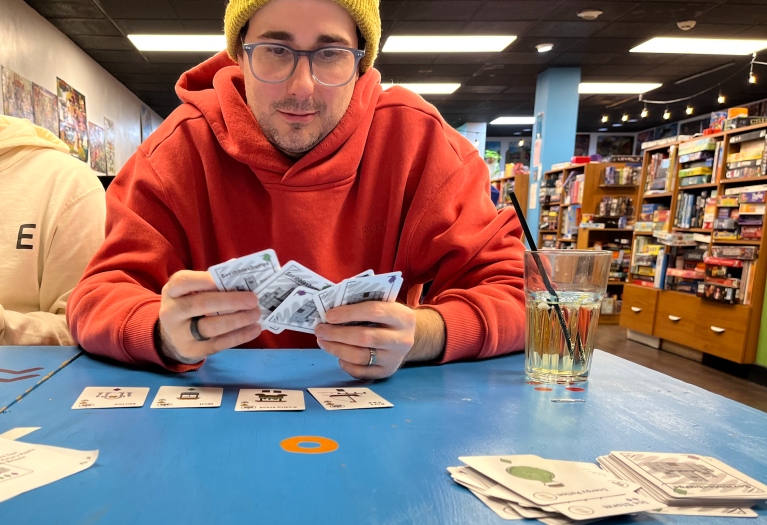 A guy in a sweater playing a card game.