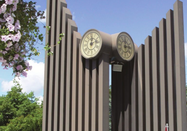 A clock tower sculpture on a sunny day.
