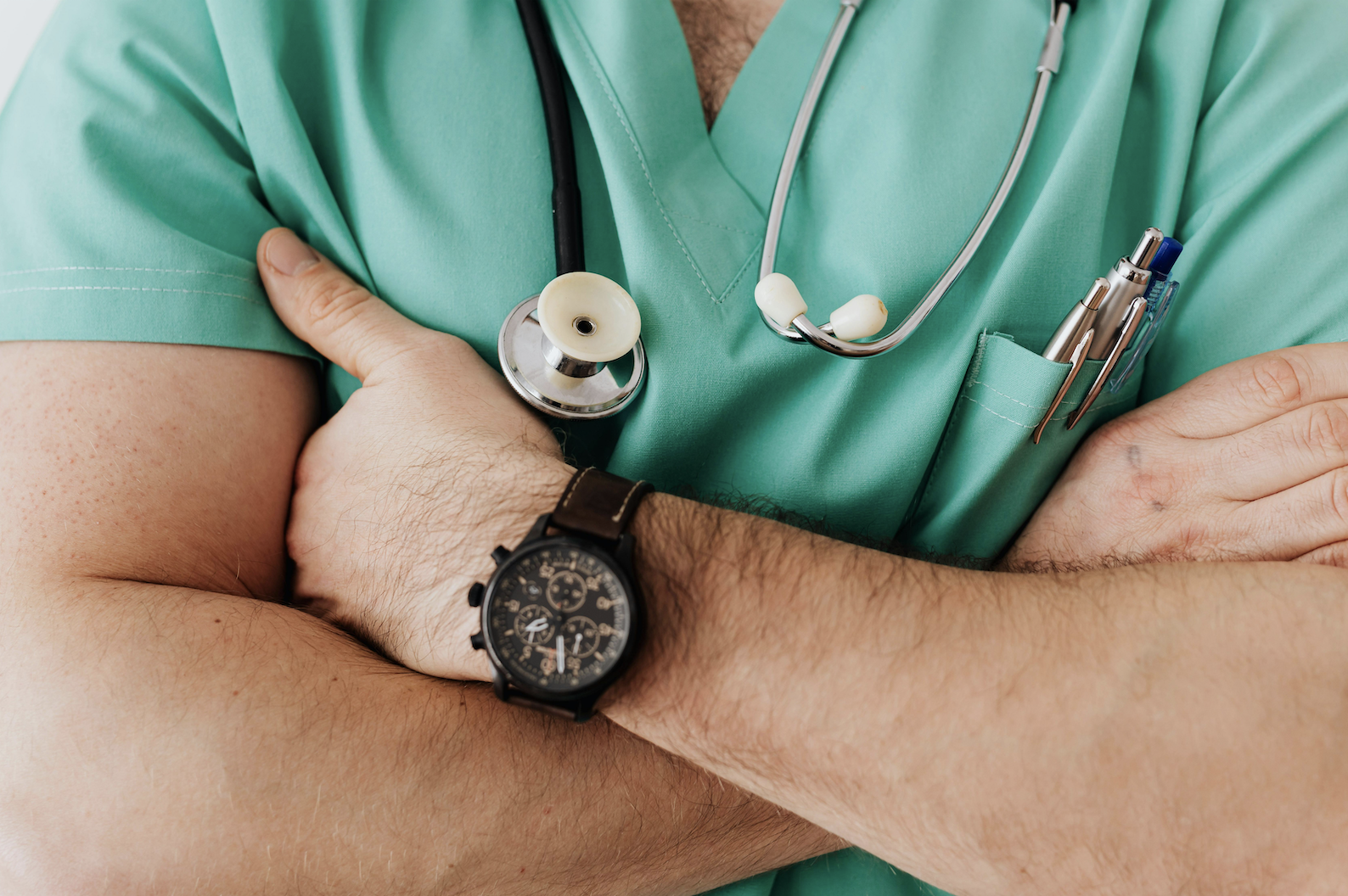 A man in scrubs with his arms folded.