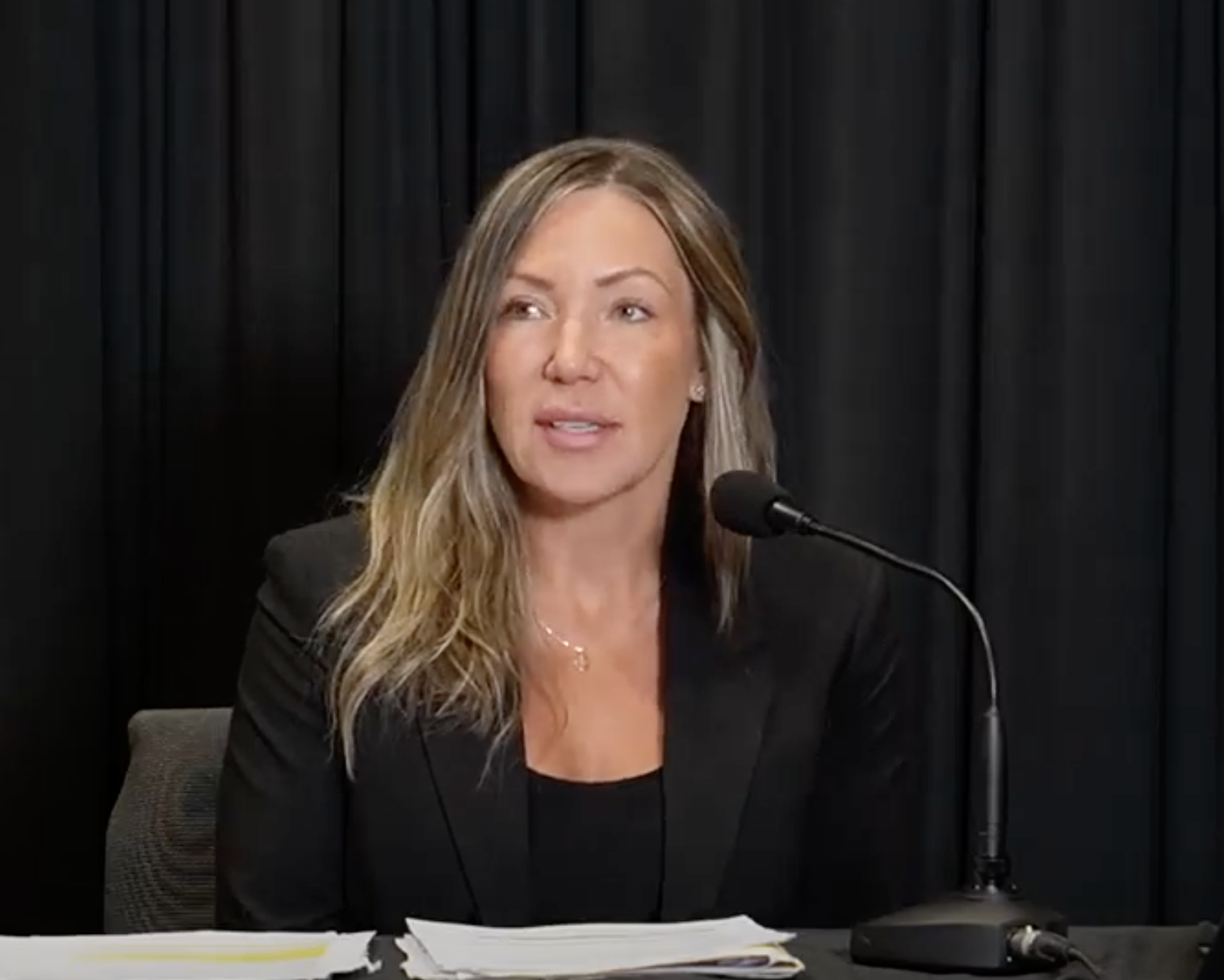 A woman in front of a microphone in a black jacket.
