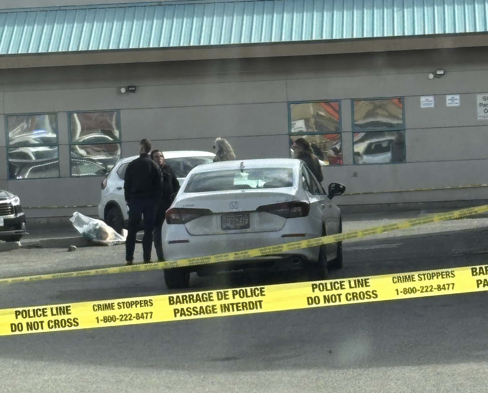 Police officers in a parking lot with police tape.