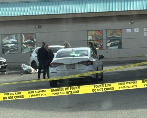 Police officers in a parking lot with police tape.