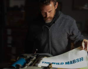 A guy in dramatic lighting print on a printing press.