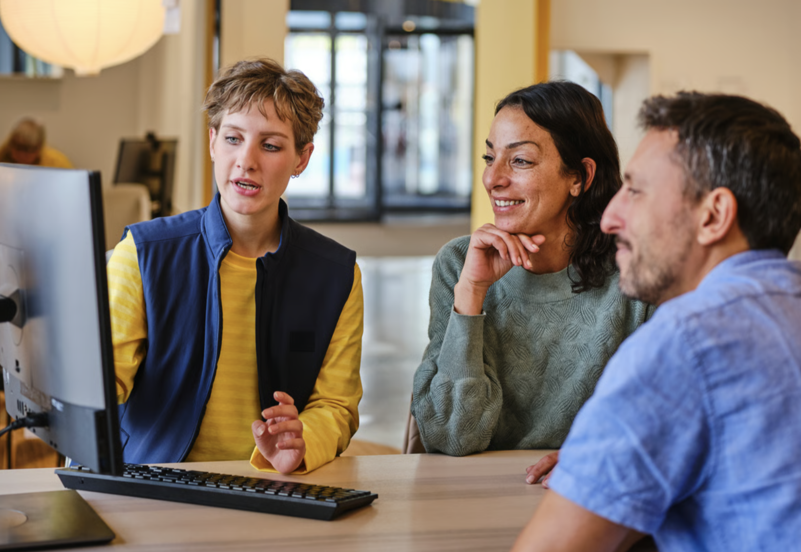Three people smiling at a computer.