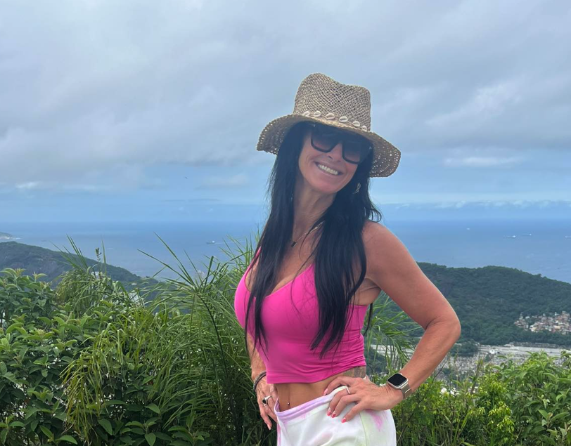 A woman wearing a pink top with the sea.