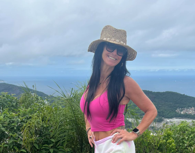 A woman wearing a pink top with the sea.