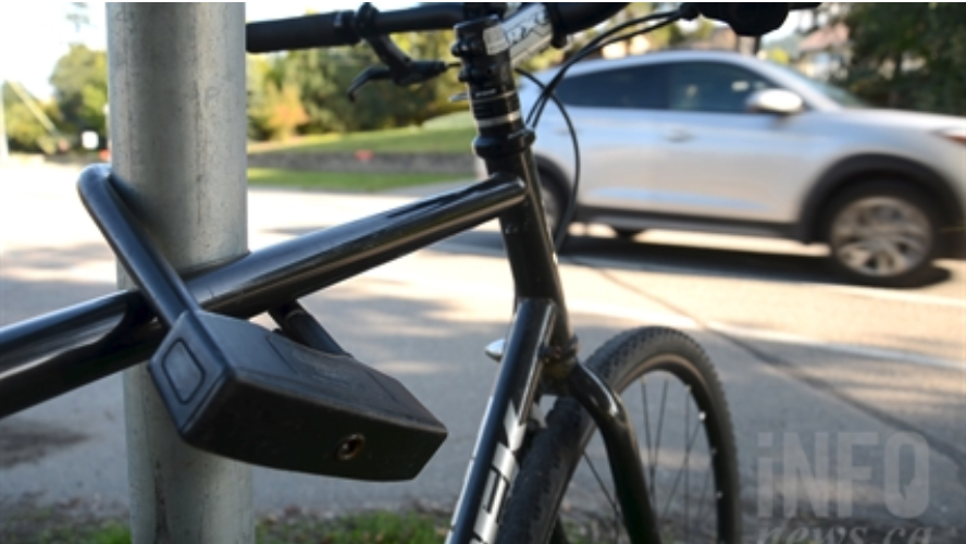 A car passes in the background of a locked up bicycle.