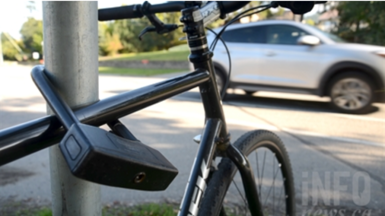 A car passes in the background of a locked up bicycle.