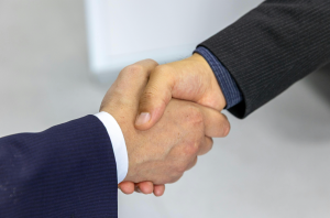Two people wearing suits shake hands.
