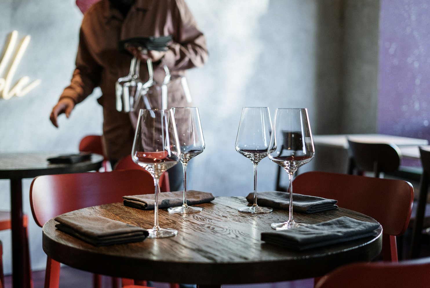A table set for dinner at a restaurant with a server in the background.