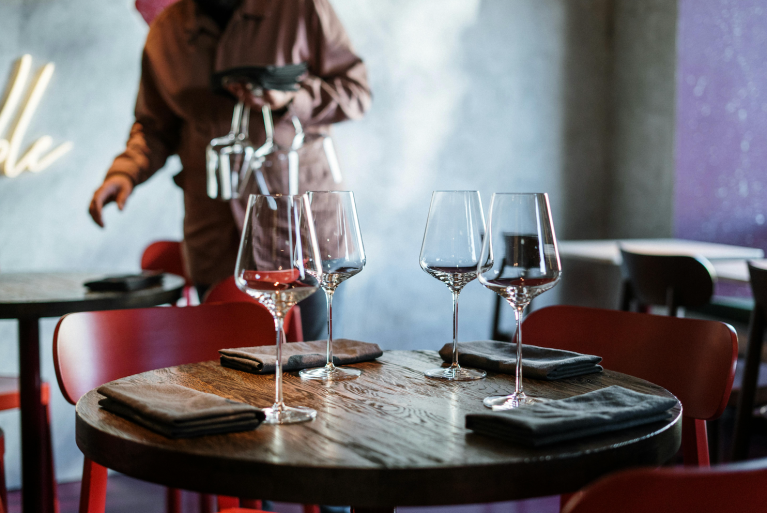 A table set for dinner at a restaurant with a server in the background.