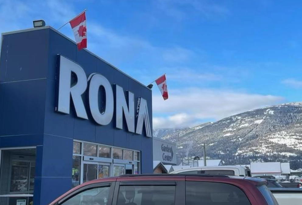 Rona hardware store against a blue sky and snow covered hills.
