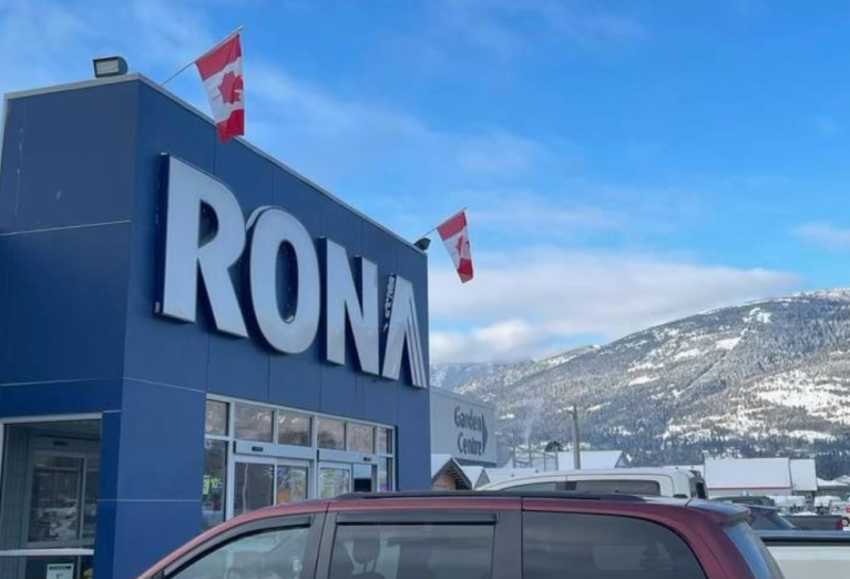 Rona hardware store against a blue sky and snow covered hills.