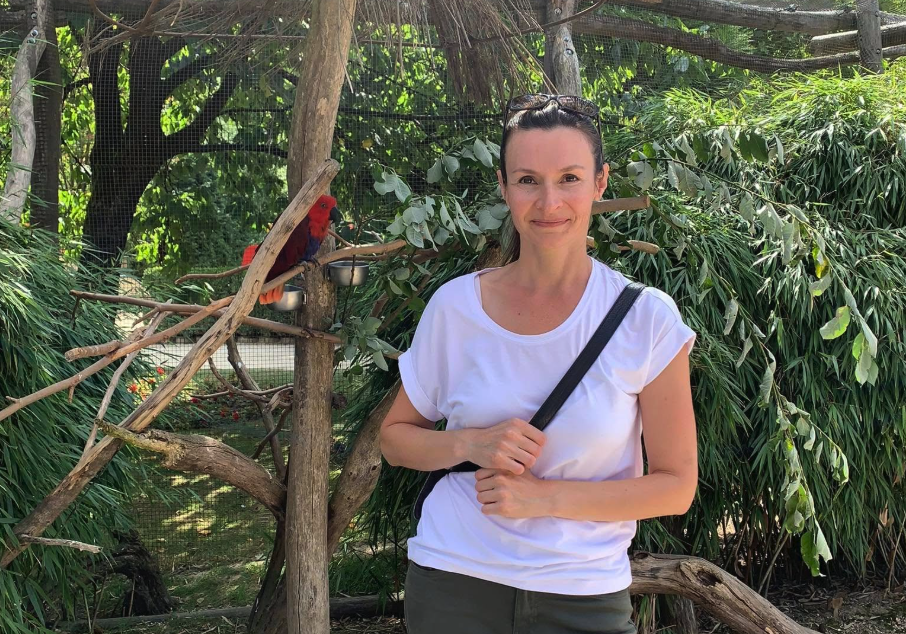 A woman in a white top with a parrot.