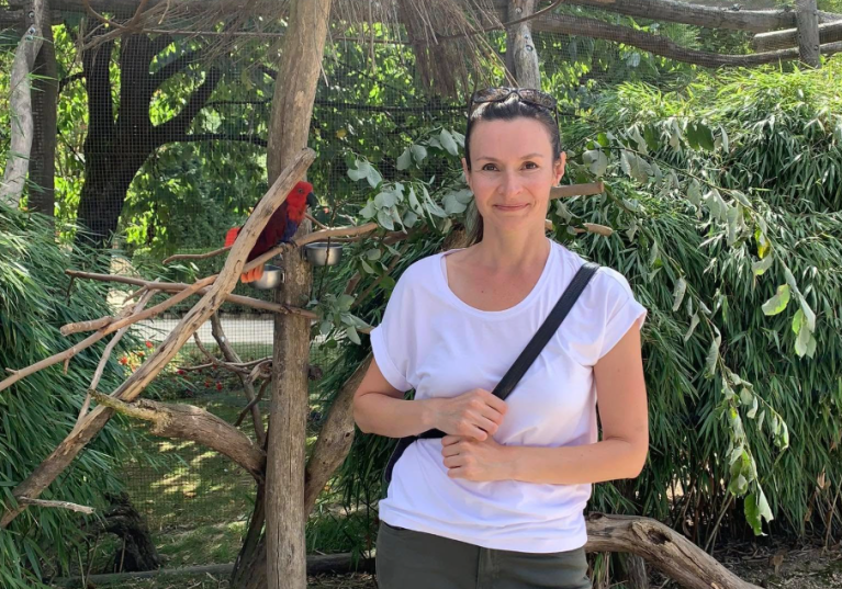 A woman in a white top with a parrot.