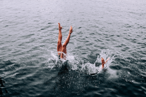 Two people diving into a lake. You can only see their legs.