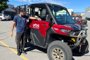 A man stands beside a red side-by-side vehicle.