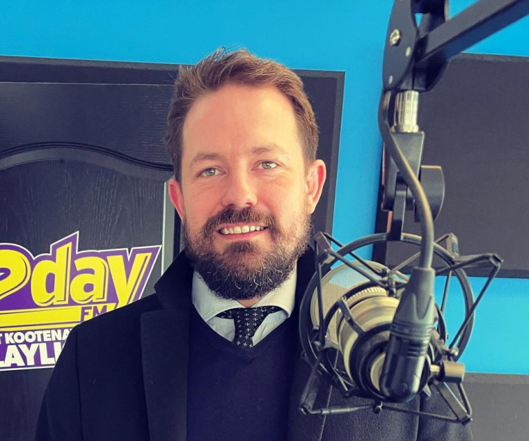 A man with a beard stands in front of a microphone.