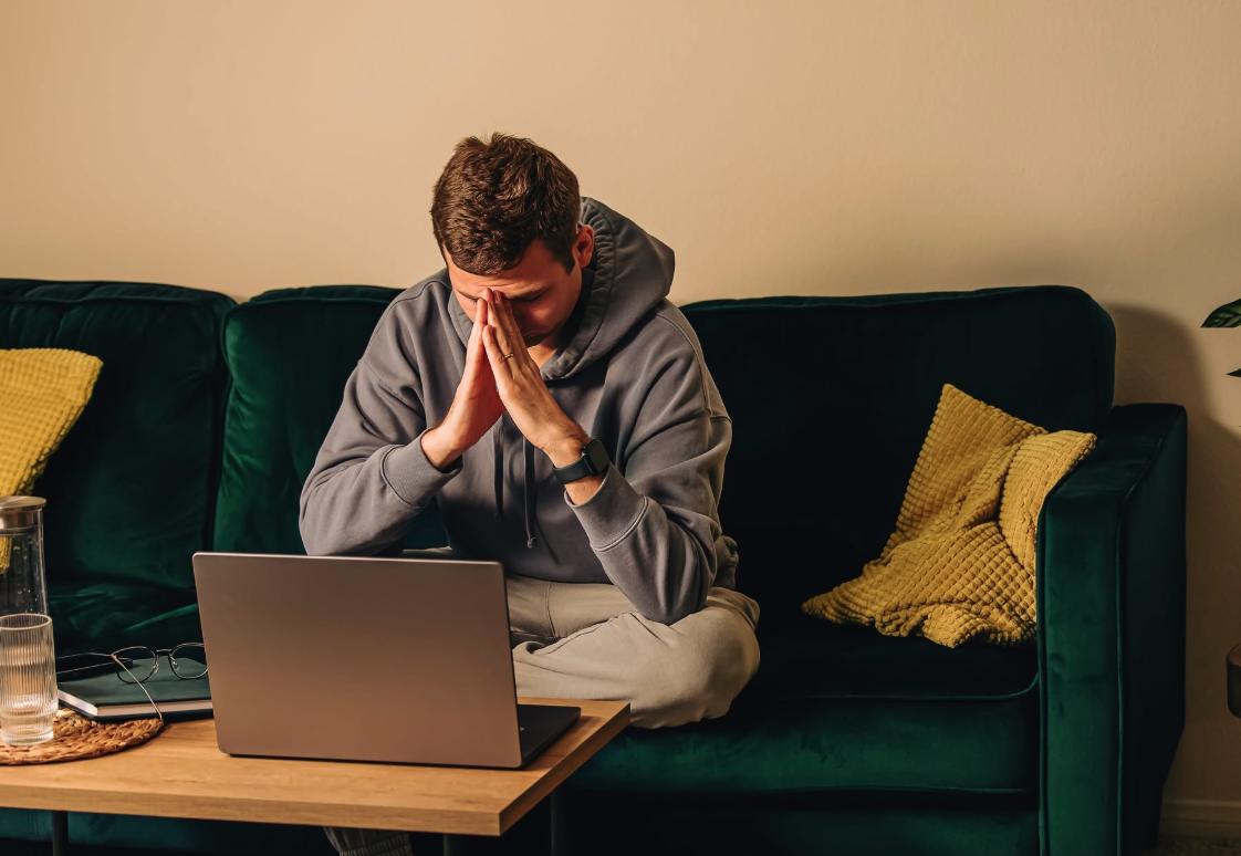 a man sits on the coach in front of a computer.