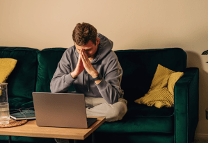 a man sits on the coach in front of a computer.