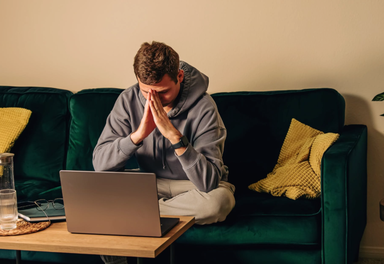 a man sits on the coach in front of a computer.