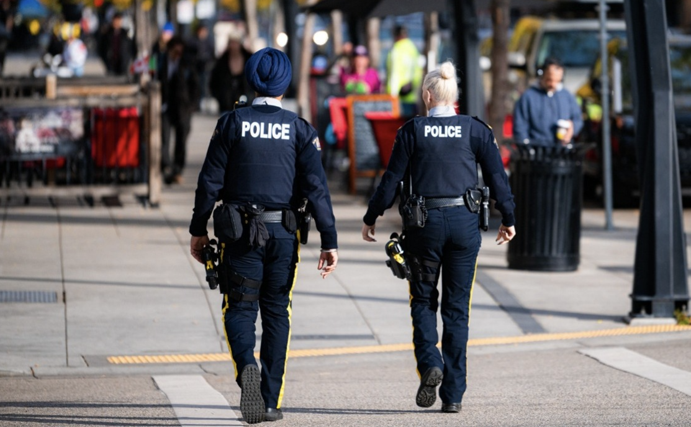 Two police officers walking in a crosswalk.