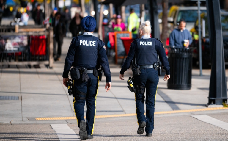 Two police officers walking in a crosswalk.