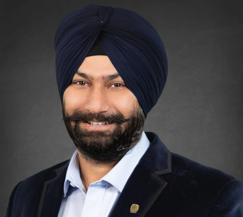 A bearded man wearing a turban, a suit jacket and a shirt