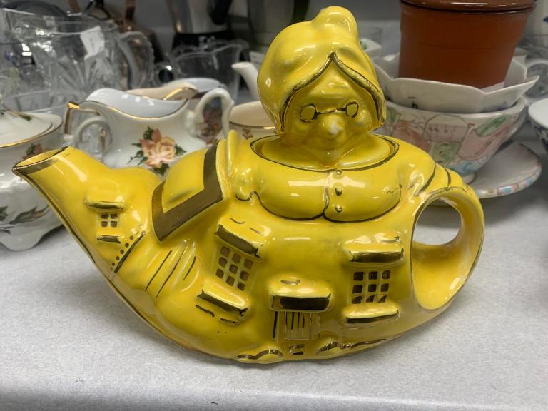 A yellow teapot looks like a house with a granny's head on top.