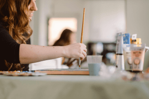 An artist paints with a brush and paint.