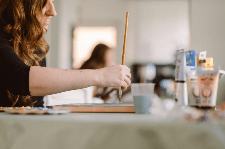 An artist paints with a brush and paint.