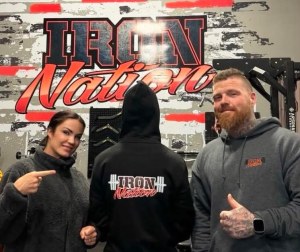 A couple point at a person in a hoodie.