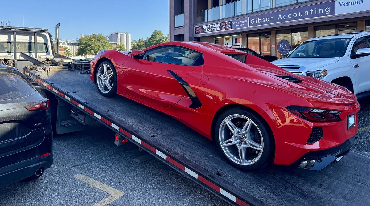 A red 2025 Corvette is being loaded onto a tow truck.