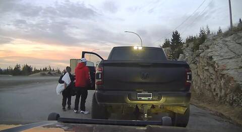 A man and his son take belongings out of a Dodge pickup parked on the side of a highway.